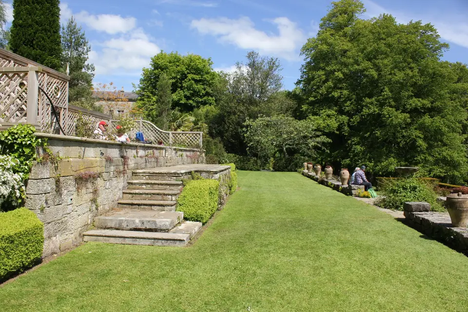 Stone terrace walls and wide steps separating two levels of a lawn garden